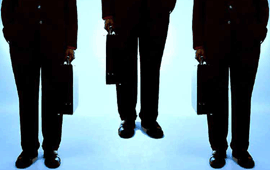 Three businessmen holding briefcases from the waist down.
