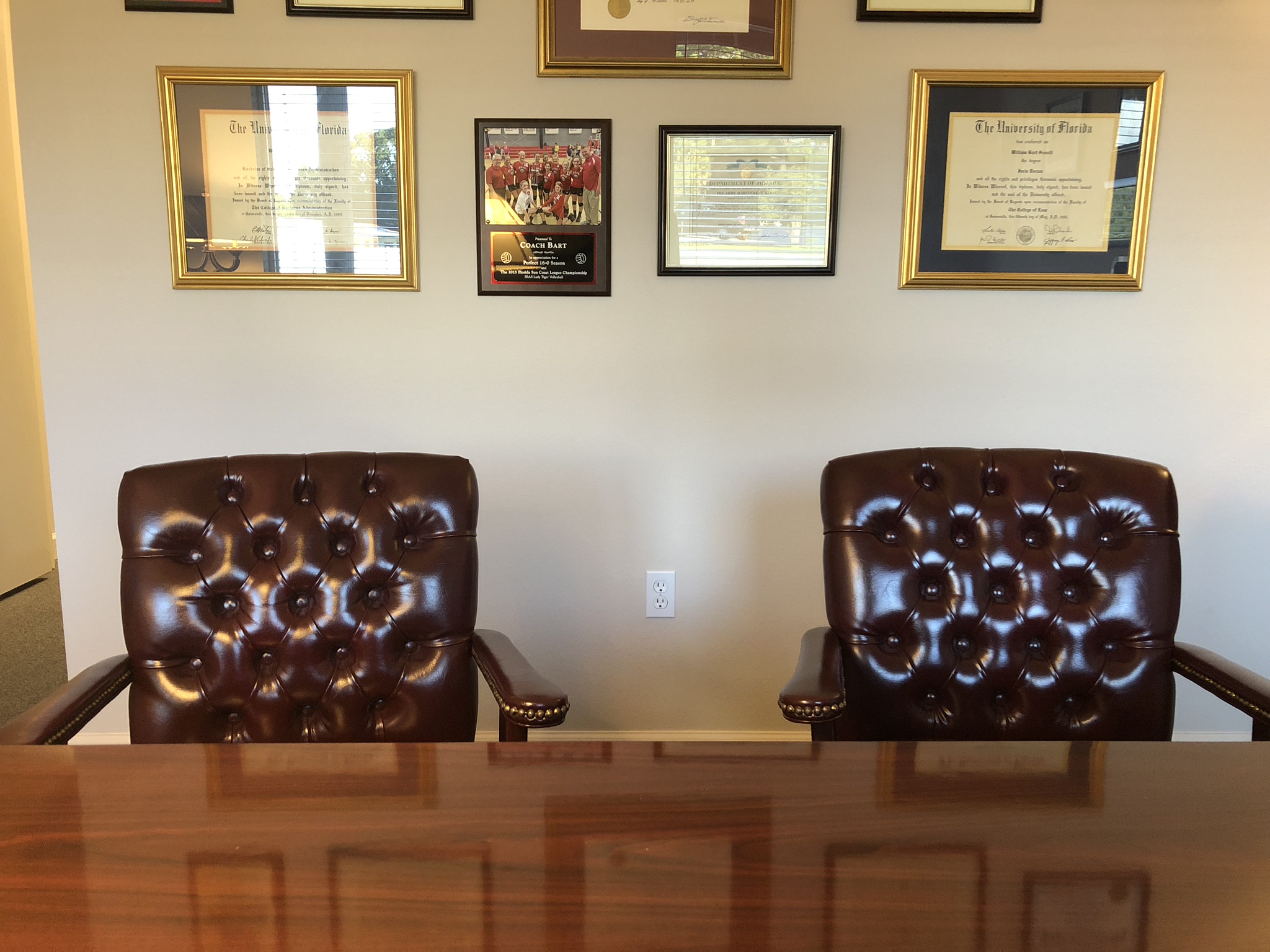 A desk, two chairs and a diploma wall