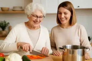 Smiling adult daughter cooking with elderly mother in a bright kitchen