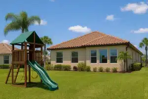 Florida backyard with stucco home, tile roof, palm trees, and a wooden playset representing family homestead protection laws